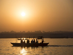 Silhouette of passengers on boat over river during sunrise in Varanasi, Uttar Pradesh Silhouette of passengers on boat over river during sunrise in Varanasi, Uttar Pradesh