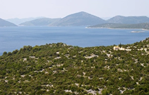 A small chapel overlooking the sea on the coast. A single cypress tree. Dry arid hill side A small chapel overlooking the sea on the coast. A single cypress tree. Dry arid hill side
