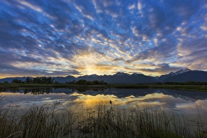 Small pond reflects the Mission Mountains at sunrise in the Ninepipe WMA in the Mission Small pond reflects the Mission Mountains at sunrise in the Ninepipe WMA in the Mission