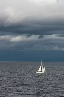 Sailboat Gallery: A small sailboat makes its way through the waters of Puget Sound under dark storm clouds