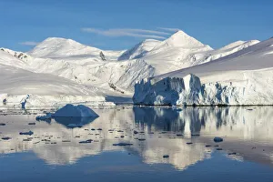 Snow covered island and iceberg with reflection in South Atlantic Ocean, Antarctica Snow covered island and iceberg with reflection in South Atlantic Ocean, Antarctica