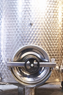 Stainless steel fermentation and storage tanks in the underground cellar. Detail of door Stainless steel fermentation and storage tanks in the underground cellar. Detail of door