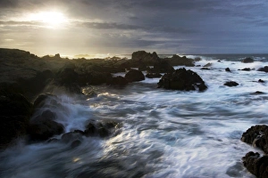 The sun breaks through storm clouds along the California Coast as surf breaks The sun breaks through storm clouds along the California Coast as surf breaks