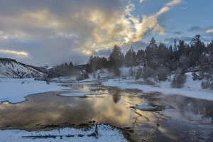 Sunrise clouds reflect into Grassy Spring in winter in Yellowstone National Park
