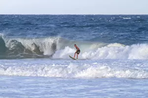 Surfer riding pacific ocean waves off the island coast of Kauai, Hawaii, USA