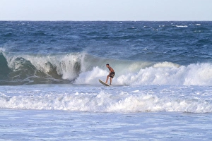 Surfer riding pacific ocean waves off the island coast of Kauai, Hawaii, USA Surfer riding pacific ocean waves off the island coast of Kauai, Hawaii, USA