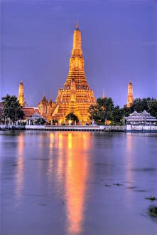 Thailand, Bangkok, Wat Arun.Ornate Buddhist temple reflects in river at dusk. Credit as