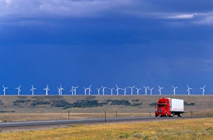 A truck traveling on the highway with a row of windmills in the background in Arlington A truck traveling on the highway with a row of windmills in the background in Arlington