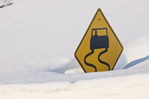 USA, Colorado. A slippery when wet sign buried in snow USA, Colorado. A slippery when wet sign buried in snow