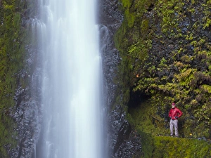 USA, Oregon. A man in red stands aside Tunnel Falls in a fall color scene on Eagle USA, Oregon. A man in red stands aside Tunnel Falls in a fall color scene on Eagle