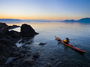 USA, Washington State, San Juan Islands, Doe Island. Woman sea kayaker paddling at dawn USA, Washington State, San Juan Islands, Doe Island. Woman sea kayaker paddling at dawn