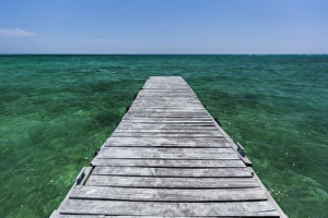 A wood dock in the foreground with clear green water and blue skies near the Isle of Youth A wood dock in the foreground with clear green water and blue skies near the Isle of Youth
