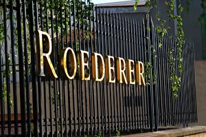 Wrought iron fence with golden letters shining in the setting sun at Champagne Louis Roederer