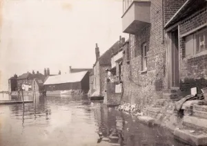 Prints of With the tide right up against the buildings, a woman can be seen doing her laundry John Fletcher Collection West Sussex Record Office, Ref No PH 26114/31 Sussex Prints: Print of Bosham at high tide, 1903