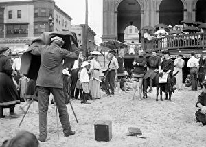 ATLANTIC CITY: BEACH. A photographer on a crowded beach taking a picture of a group of three people with a donkey