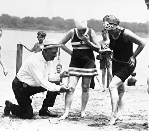 BATHING SUITS, 1922. A Public Buildings and Grounds officer measures womens bathing suits to ensure they are not more