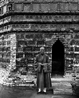 A Buddhist monk standing outside the entrance of the Iron Pagoda A Buddhist monk standing outside the entrance of the Iron Pagoda