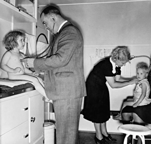 A doctor and nurse examining children in a trailer clinic at a mobile camp for migrant A doctor and nurse examining children in a trailer clinic at a mobile camp for migrant