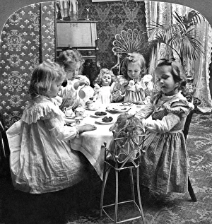 Daily Life Gallery: Four girls and their dolls sitting around a table and having a tea party. Stereograph, c1902