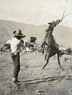 Images Dated 12th May 2010: TEXAS: COWBOY, c1910. A cowboy holding a rope around the neck of a bucking bronco on a ranch in