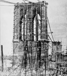 Print of the Brooklyn Bridge under construction over the East River