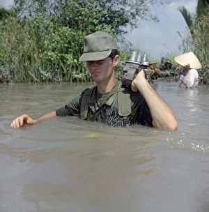 VIETNAM WAR, 1967. Private Daniel Bauer, a filmmaker with DASPO, crossing an irrigation VIETNAM WAR, 1967. Private Daniel Bauer, a filmmaker with DASPO, crossing an irrigation