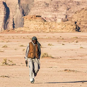 A man walking through the desert at Wadi Rum, Jordan A man walking through the desert at Wadi Rum, Jordan