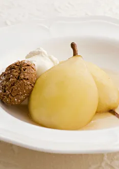 Two baked pears in Marsala with amaretti biscuits and whipped cream, close-up Two baked pears in Marsala with amaretti biscuits and whipped cream, close-up