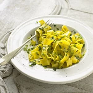 Bowl of tagliatelle pasta with basil, parsley and oregano pesto, with fork