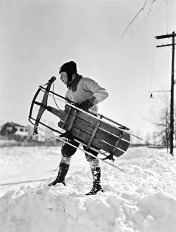 <b class=qtipBold><figcaption>A Boy Carrying His Sled</figcaption></b><br>New York: c. 1935 A boy wearing a leather cap with goggles carrying his sled for a day in the snow.<br><em>© Underwood Archives/UIG</em> A Boy Carrying His Sled