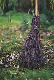 Close-up of a broomstick sweeping autumn leaves from a damp garden lawn Close-up of a broomstick sweeping autumn leaves from a damp garden lawn