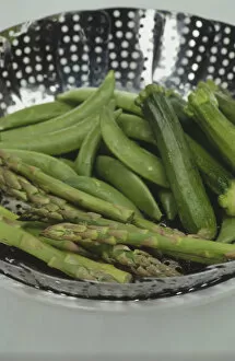Colander containing courgettes, green beans and asparagus, close up
