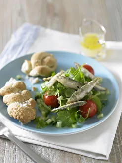 Fried whitebait on bed of green salad with tomato and bread rolls Fried whitebait on bed of green salad with tomato and bread rolls