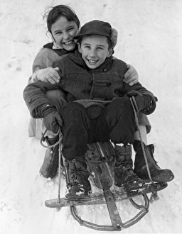 <b class=qtipBold><figcaption>Happy Children On A Sled</figcaption></b><br>United States: c. 1955. Two smiling children sitting on a sled in the snow.<br><em>© Underwood Archives/UIG</em> Happy Children On A Sled