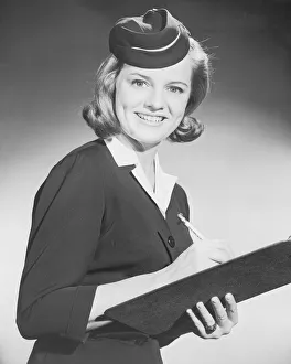 Historic portrait of airline stewardess with clipboard and pencil, 1950-60s Historic portrait of airline stewardess with clipboard and pencil, 1950-60s