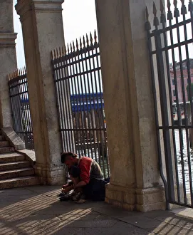 Italy, Venice, Beggar sitting in front of metal fence Italy, Venice, Beggar sitting in front of metal fence