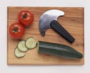 Kitchen knife with half moon blade on chopping board with tomatoes and cucumber Kitchen knife with half moon blade on chopping board with tomatoes and cucumber