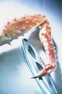 Leg of Alaskan King Crab next to metal lobster cracker, close-up Leg of Alaskan King Crab next to metal lobster cracker, close-up