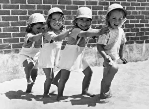 <b class=qtipBold><figcaption>Four Little Girls Having Fun</figcaption></b><br>United States: 1952 Four little girls marching across the sand in their sun dresses.<br><em>© Underwood Archives/UIG</em> Four Little Girls Having Fun