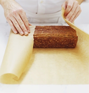 Loaf of rye bread being wrapped in brown paper, side paper Loaf of rye bread being wrapped in brown paper, side paper