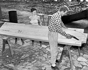 <b class=qtipBold><figcaption>Making A Surfboard</figcaption></b><br>Santa Cruz, California: c. 1959. A surfer cuts out his new board with a saw while his girlfriend holds things steady.<br><em>© Underwood Archives/UIG</em> Making A Surfboard
