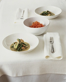 Monkfish curry with carrot salad arranged in bowls on a table Monkfish curry with carrot salad arranged in bowls on a table