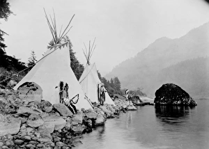 Three Native American men, probably Umatilla, stand on shore of river next to tepees Three Native American men, probably Umatilla, stand on shore of river next to tepees