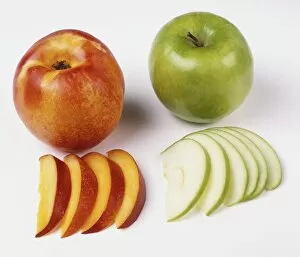 A nectarine and a green apple, whole and cut in slices