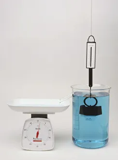 Newton meter pulled by weight immersed in water with scales showing upthrust Newton meter pulled by weight immersed in water with scales showing upthrust