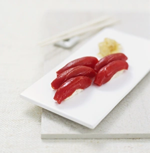 Nigiri sushi parcels made from rice topped with raw tuna slices, on a white board Nigiri sushi parcels made from rice topped with raw tuna slices, on a white board