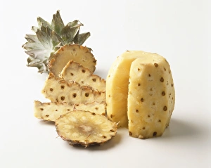 Peeled pineapple with section removed displayed next to its skin, close up Peeled pineapple with section removed displayed next to its skin, close up