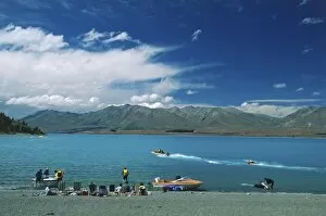 People sitting on the banks of Lake Tekapo, South Island, New Zealand, a popular venue for water sports