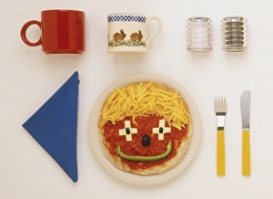 Pizza decorated as a smiley face, blue napkin, salt and pepper shakers, two mugs Pizza decorated as a smiley face, blue napkin, salt and pepper shakers, two mugs