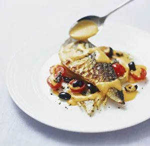 Romesco sauce being spooned over grilled mackerel fillet served with black olives Romesco sauce being spooned over grilled mackerel fillet served with black olives
